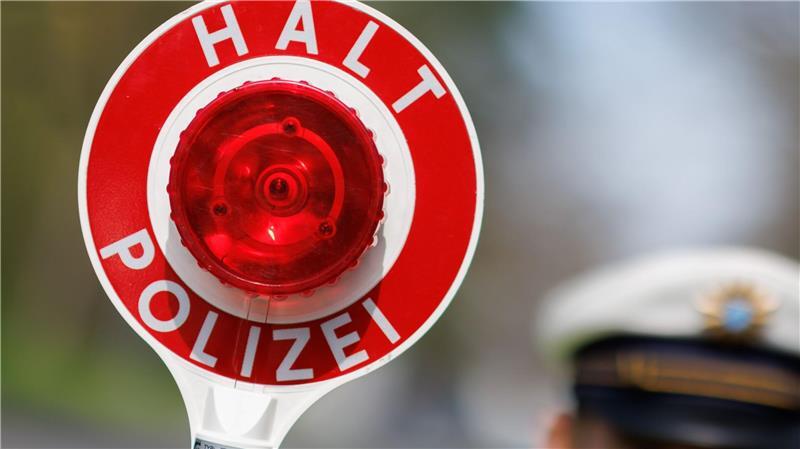 Ein Polizist zieht ein Fahrzeug mit seiner Kelle aus dem Verkehr.