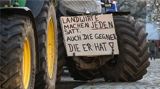 Ein Protestplakat mit der Aufschrift «Landwirte mache jeden satt, auch die Gegner die er hat!» ist bei einer Demonstration in Magdeburg an einem Traktor befestigt.