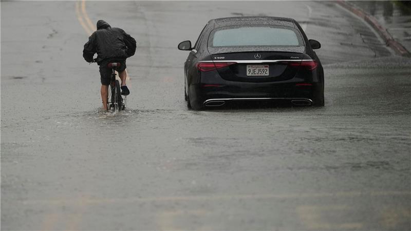 Ein Radfahrer fährt durch eine überflutete Straße.