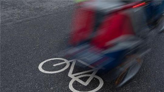 Ein Radfahrer fährt mit einem Anhänger über einen Fahrradweg.