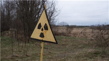 Ein Radioaktivitäts-Warnzeichen, im Hintergrund das Kernkraftwerk Tschernobyl, aufgenommen am 9. April 2026. 