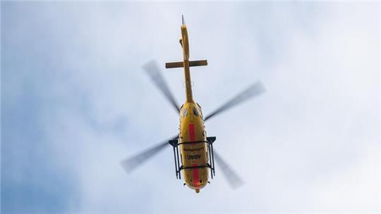 Ein Rettungshubschrauber der ADAC fliegt am Himmel entlang.