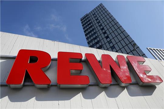 Ein Rewe Schriftzug hängt vor einem Supermarkt. Foto: picture alliance/dpa | Oliver Berg