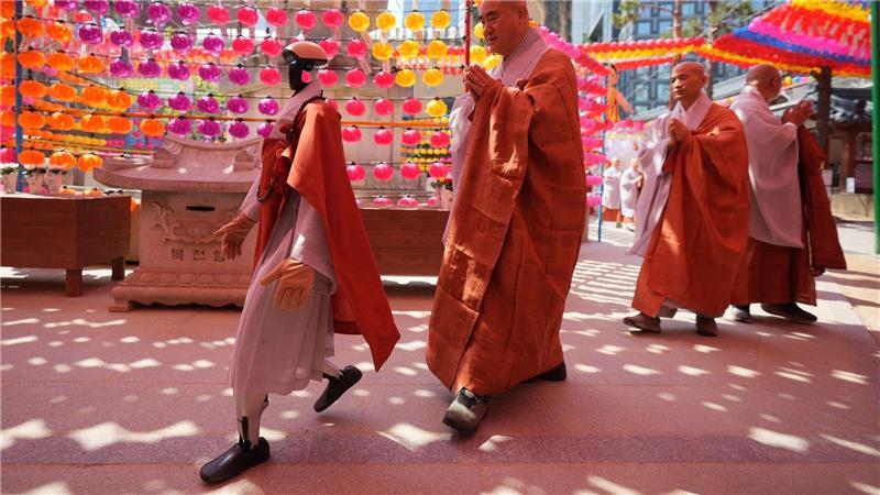 Ein Roboter und buddhistische Mönche umrunden zusammen eine Pagode während einer Zeremonie vor dem Geburtstag Buddhas im koreanischen Seoul.