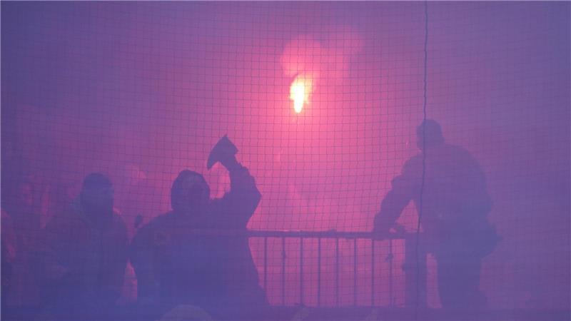 Ein Rostock-Fan wirft ein Keramik-Teil einer zerstörten Toilette auf Ordner.