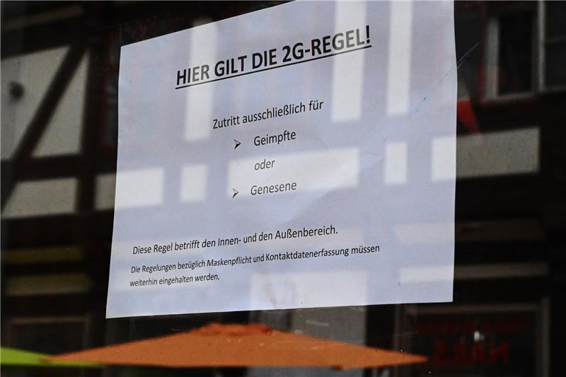 Ein Schild «Hier gilt die 2G-Regel!» hängt in einer Tür eines Cafés. Foto: Swen Pförtner/dpa