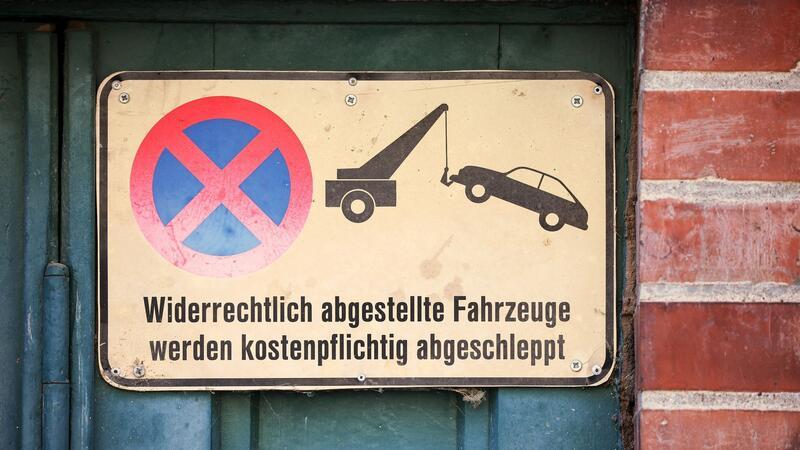 Ein Schild an einem Garagentor weist darauf hin, das widerrechtlich abgestellte Fahrzeuge abgeschleppt werden - und das kann teuer werden.