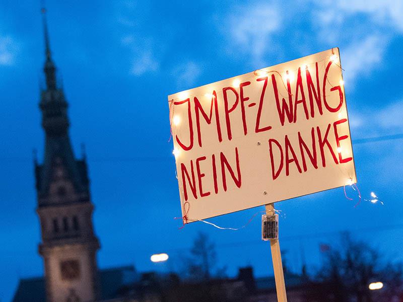 Ein Schild mit der Aufschrift "Impfzwang nein danke" wird während einer Demonstration gegen Corona-Einschränkungen in Hamburg hochgehalten. Foto: Daniel Bockwoldt/dpa