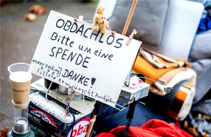 Ein Schild mit der Aufschrift „Obdachlos - bitte um eine Spende - danke!“ steht neben den Habseligkeiten eines Obdachlosen, die auf einem Bürgersteig in der Innenstadt liegen. Foto: Hauke-Christian Dittrich/dpa
