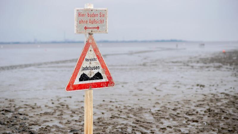 Wattenmeer seit 15 Jahren Weltnaturerbe Ein Schild mit der Aufschrift „Vorsicht Jadebusen“ steht im Wattboden am Strand von Dangast.