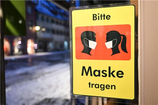 Ein Schild weist am Eingang eines Ladens auf die Maskenpflicht hin.