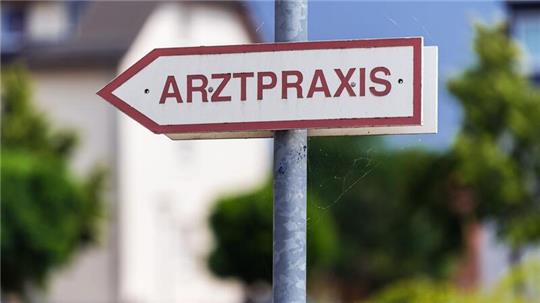 Ein Schild weist den Weg zu einer Arztpraxis.