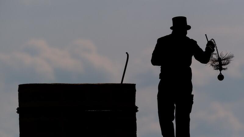 Schornsteinfeger werben um Nachwuchs Ein Schornsteinfeger mit seinem Kaminkehrerwerkzeug auf einem Dach.