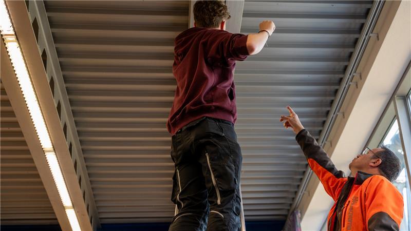 Wenn Schule Angst macht: Wie sich Tobias Schritt für Schritt zurückkämpft Ein Schüler (l) und Stefan Ressler, Hausmeister, wechseln zusammen die Glühbirne einer Deckenleuchte in einer Schule in Bayern.