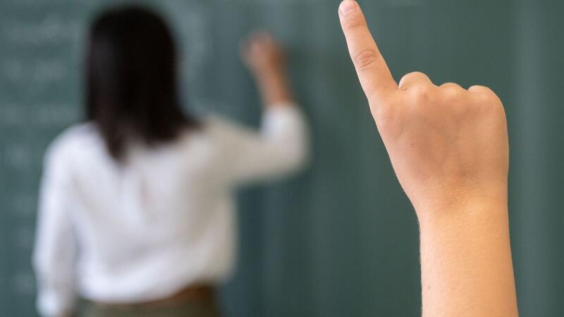 Fast 460 angehende Lehrer ins Referendariat gestartet Ein Schüler meldet sich, während die Lehrerin an die Tafel schreibt.