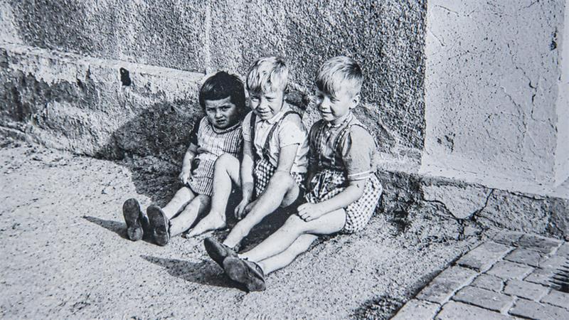 Ein Schwarz-Weiß-Foto aus den 50ern bewahrt die Erinnerung an drei Kinder, die einst gemeinsam vor dem Haus der Familie saßen. Links ist Dorothea Langwald zu sehen.