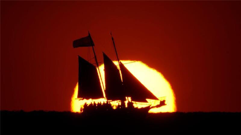 Ein Segelboot zeichnet sich gegen die untergehende Sonne ab, während es im Golf vor der Küste von Treasure Island in Florida segelt.