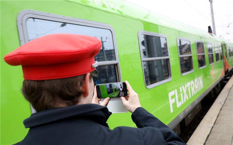 Ein Servicemitarbeiter der Deutschen Bahn filmt mit seinem Smartphone die Ausfahrt des neuen Fernzugs Flixtrain. Foto Charisius/dpa