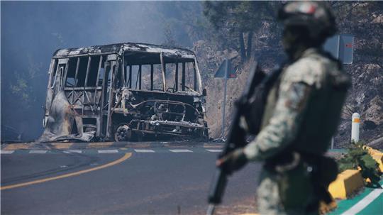 Ein Soldat steht in Mexiko - einem der drei Ausrichterländer der Fußball-WM im Sommer - neben einem ausgebrannten Bus.