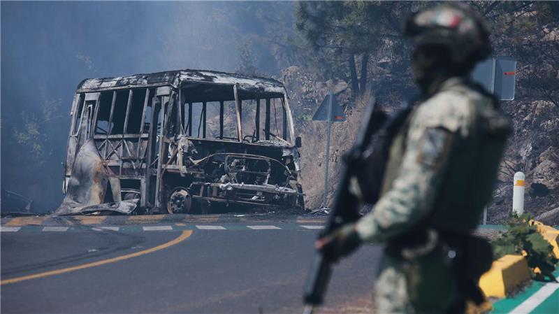 Ein Soldat steht neben einem ausgebrannten Bus, der nach dem Tod von Mexikos mächtigstem Drogenboss Nemesio Oseguera Cervantes, aka „El Mencho“, in Cointzio in Brand gesetzt wurde.