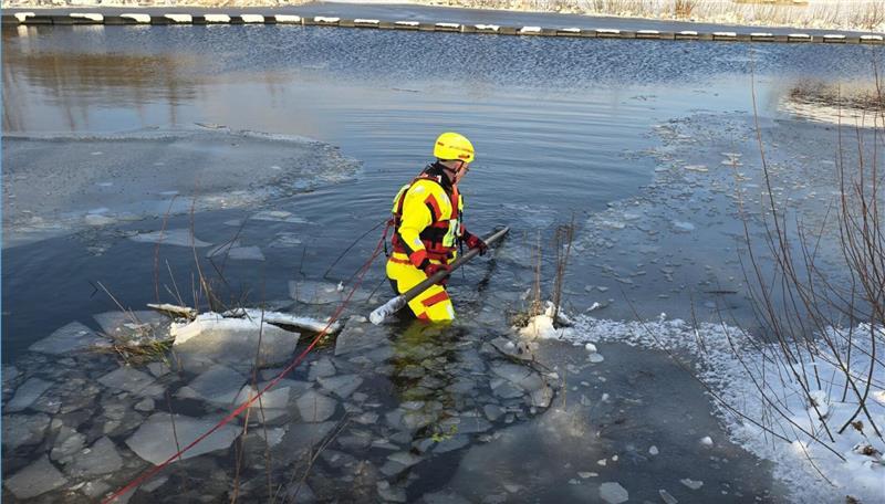 Ein Strömungsretter sucht das Regenrückhaltebecken ab. Das dünne Eis ist gebrochen.