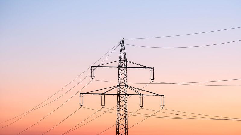 Stromsteuer-Senkung für Industrie teuer als geplant Ein Strommast bei Sonnenaufgang.