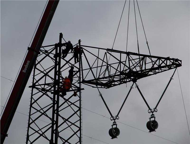 Ein Strommast entsteht : Vier Monteure schrauben eine Traverse an das Stahlfachwerkgerüst des neuen Mastprovisoriums. Das Bauteil wird mit dem Kran erst waagerecht angehoben und dann langsam aufgerichtet, um es nicht zu beschädigen. Die Män