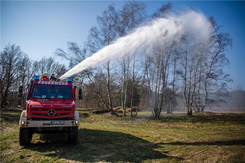 Ein TLF-W 3000 "Tanklöschfahrzeug-Waldbrand mit 3000l Wasser-Fassungsvermögen" sprüht über einen sogenannten Dachmonitor mit 2000 Litern die Minute Wasser auf ein Militär-Übungsgelände. Mehrere Feuerwehren dürfen das geländegängige Spezialfahrzeug, das auf einem Mercedes-Unimog basiert nacheinander testen. Foto: Lino Mirgeler/dpa