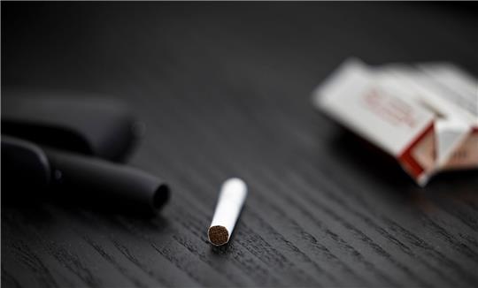 Ein Tabakstick, Stickpäckchen und Tabakerhitzer liegen auf einem Tisch. Die drei Branchenriesen haben hohe Erwartungen an den künftigen Absatz.