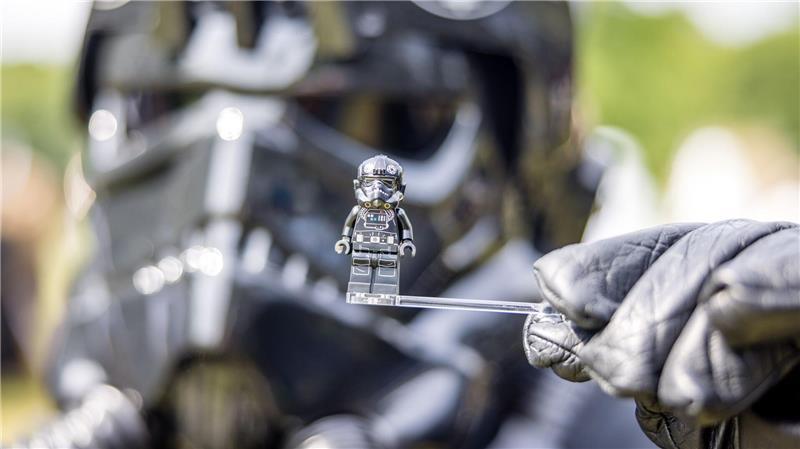 Bilder des Tages Ein Teilnehmer des Elbenwald Festivals, als Mitglied der Stormtroopers verkleidet, hält eine Figur seiner Rolle vor seinen Kopf.