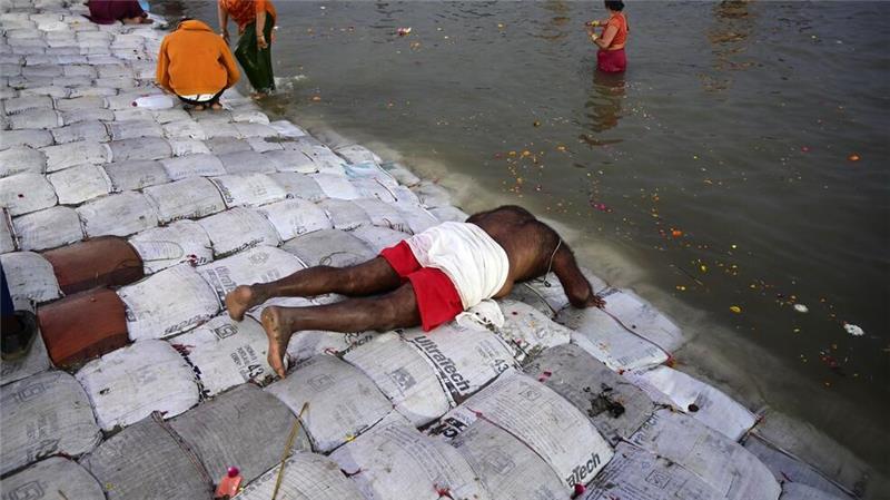 Ein Teilnehmer des Pilgerfests Maha Kumbh Mela spricht ein Gebet, bevor er ein Bad im Fluss nimmt.