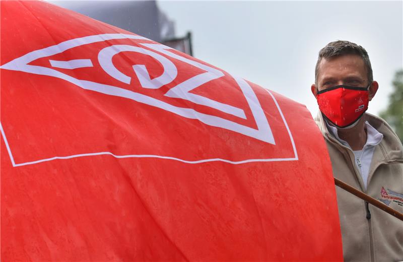 Ein Teilnehmer einer Protestaktion steht mit einer Fahne der IG Metall auf dem Firmengelände der Airbus-Tochter Premium Aerotec. Foto: Karl-Josef Hildenbrand/dpa