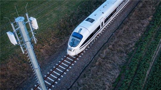 Ein Testzug der Deutschen Bahn fährt an einer der Antennenmasten für das 5G-Bahnprojekt vorbei.