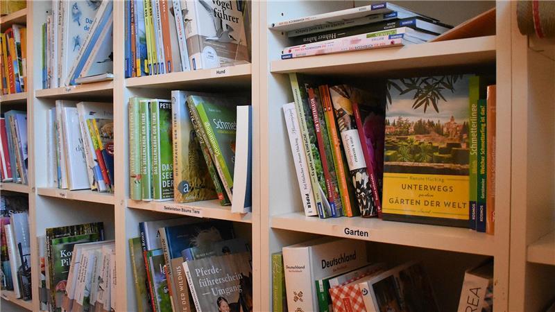 In Freiburg bestimmt eine Hündin den Spitznamen des Buchcafés Ein weißes Bücherregal mit Büchern aus verschiedenen Genres.