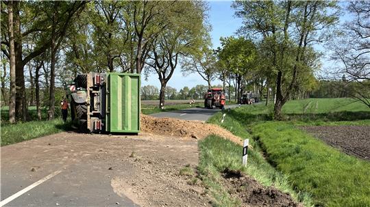Ein Trecker-Gespann liegt auf der Straße; Sand verteilt sich über die Fahrbahn.