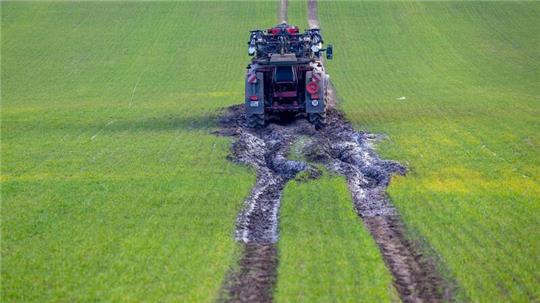 Ein Traktorgespann ist beim Ausbringen von Dünger im aufgeweichten Boden auf einem Feld steckengeblieben.