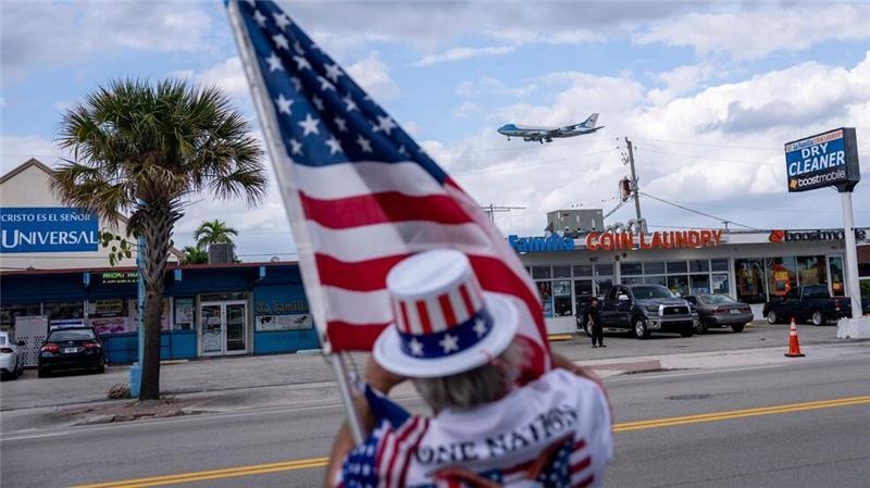 Ein Unterstützer hält eine US-Flagge und beobachtet, wie die Air Force One mit US-Präsident Trump an Bord auf dem Palm Beach International Airport landet.