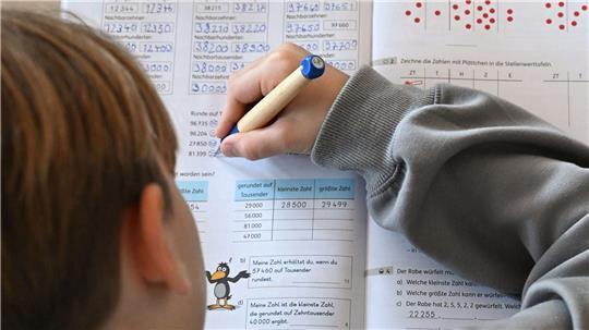 Ein Viertklässler arbeitet in seinem Matheheft. (Symbolbild)