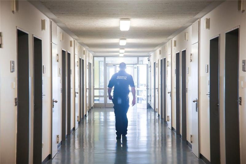 Ein Vollzugsbeamter geht in der JVA Billwerder in Hamburg einen Gang entlang. Foto: Ulrich Perrey/dpa