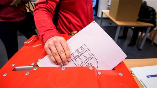 Ein Wähler steckt in einem Wahllokal seine Stimmzettel zur Europawahl und zur Bezirksversammlungswahl in die Wahlurne.