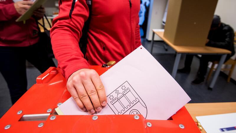 Bange Blicke auf Auszählung der Hamburger Bezirkswahl Ein Wähler steckt in einem Wahllokal seine Stimmzettel zur Europawahl in die Urne.