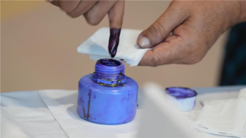 Ein Wähler taucht seinen Finger in ein Tintenfass.