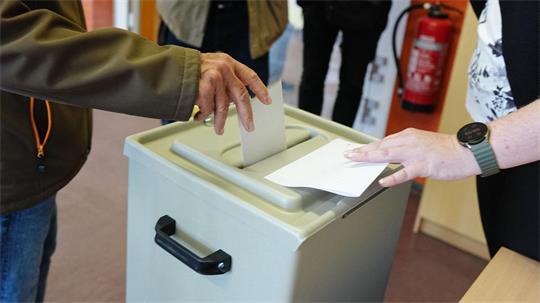 Ein Wähler wirft seinen gefalteten Stimmzettel in die Wahlurne in einem Wahllokal.