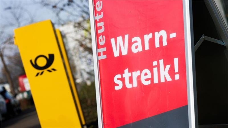 Post-Warnstreiks: Jeder zehnte Brief bleibt vorerst liegen Ein Warnstreik-Schild bei einem Post-Standort, daneben ein Briefkasten - im Ringen um einen Tarifabschluss haben Tausende Postler erneut die Arbeit niedergelegt.