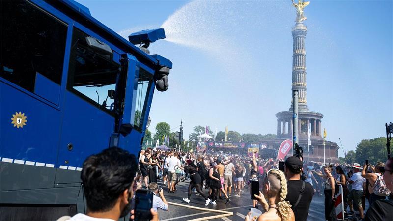 Ein Wasserwerfer der Polizei verschafft den Ravern etwas Abkühlung.  