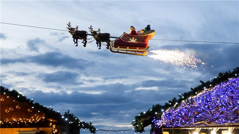 Ein Weihnachtsmann in einem fliegenden Schlitten ist in Montreux über den Weihnachtsständen vom Weihnachtsmarkt unterwegs.