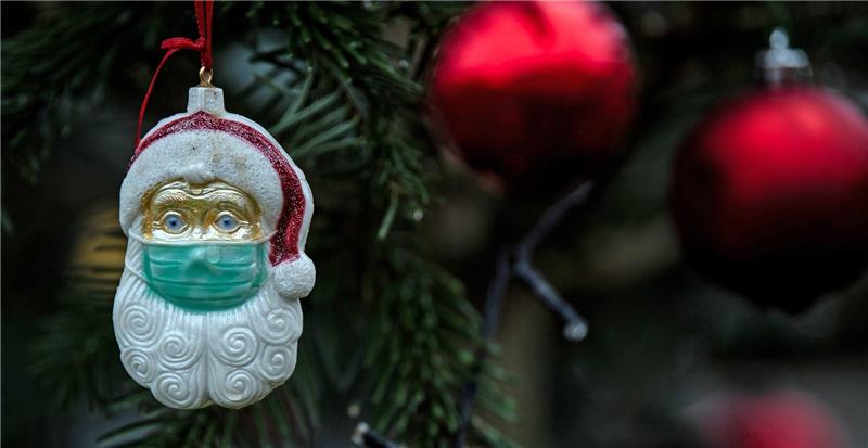 Ein Weihnachtsmann mit einer Schutzmaske hängt als Weihnachtsbaumschmuck in einem Tannenbaum. Foto: Federico Gambarini/dpa