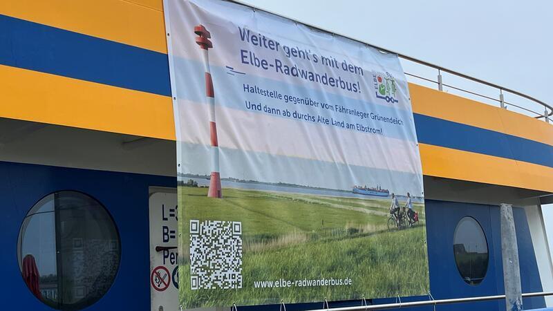 Ein Werbebanner des Elbe-Radwanderbusses hängt in der Saison an der Lühe-Schulau-Fähre.