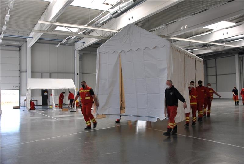 Ein Zelt schwebt durch die große Halle: Ehrenamtliche Helfer der DLRG errichten Zeltdörfer in der Gewerbehalle in Stade-Ottenbeck. Fotos: Lohmann