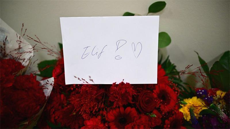 Ein Zettel mit der Aufschrift „Elif!“ steckt in einem Blumenstrauß.
